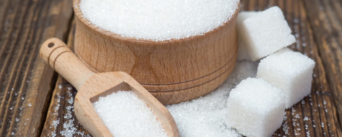 Stack of sugar cubes and granulated sugar in a wooden scoop
