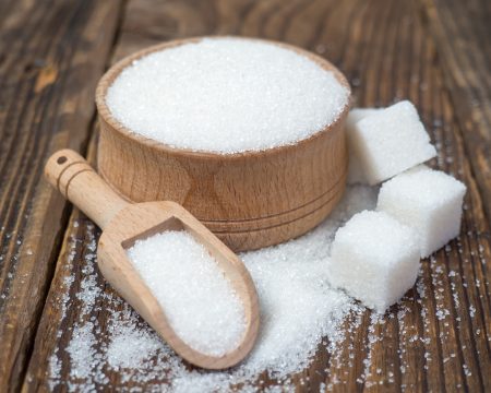 Stack of sugar cubes and granulated sugar in a wooden scoop