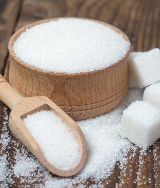 Stack of sugar cubes and granulated sugar in a wooden scoop